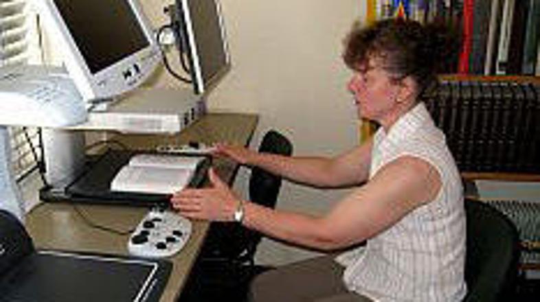 Bibliotekarka Dani Jurgec demonstrira branje z elektronskim povečevalom.