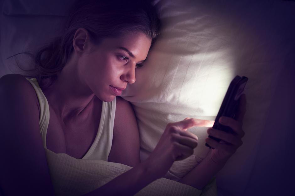 Ženska pregleduje telefon v postelji ponoči | Avtor: Profimedia