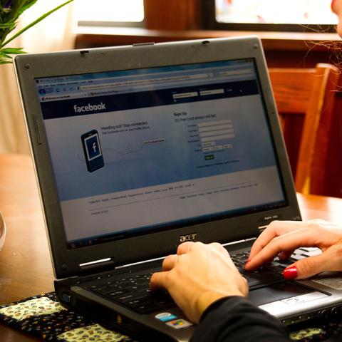 Ženska ob računalniku ima odprt Facebook