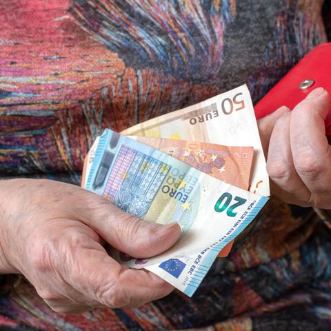Upokojenka drži v rokah evre in denarnico