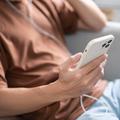 moški drži v roki telefon in posluša glasbo