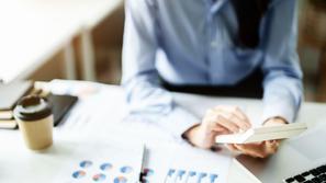 Ženska na računalniku s kalkulatorjem