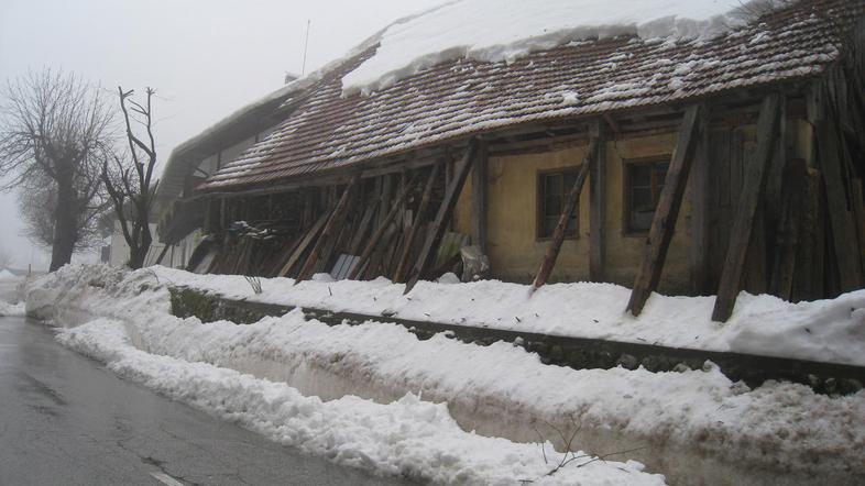 Staro in dotrajano gospodarsko poslopje podprto z lesenimi tramovi ječi pod težo