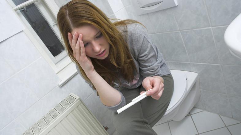 ženska s testom nosečnosti