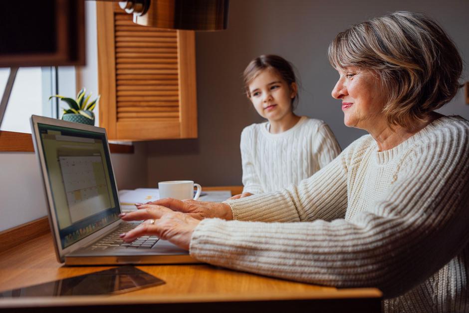 Starejša ženska za računalnikom ob punčki | Avtor: Profimedia