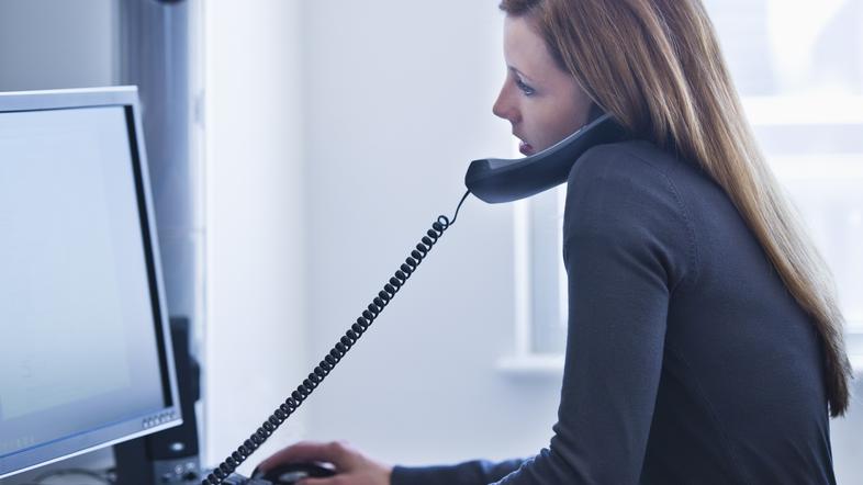 Ženska telefonira ob računalniku