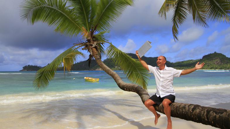 moški z računalnikom na plaži