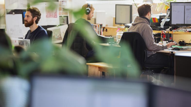 Moški s slušalkami v pisarni za računalniki