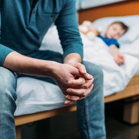 oče sedi na bolniški postelji ob sinu