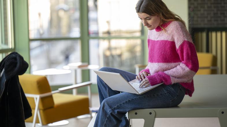 Mlada ženska z računalnikom v kavarni