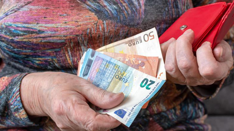 Upokojenka drži v rokah evre in denarnico