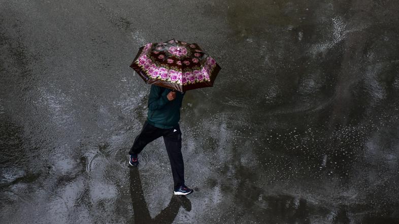 moški z dežnikom hodi po ulici dež