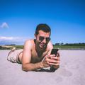 Moški uporablja mobilni telefon na plaži