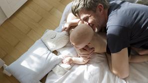 oče z dojenčkom leži na postelji