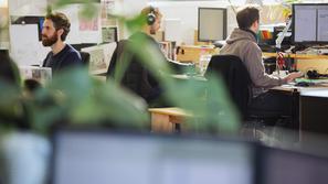 Moški s slušalkami v pisarni za računalniki