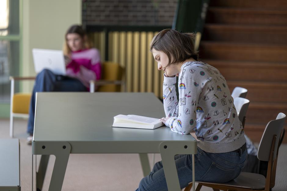 Mlada punca sedi za mizo in bere knjigo | Avtor: Profimedia