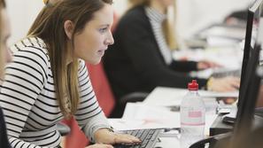 Mlada ženska sedi za računalnikom