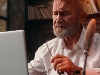 Starejši moški z očali ob računalniku