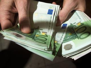 Moški v roki drži denar evre