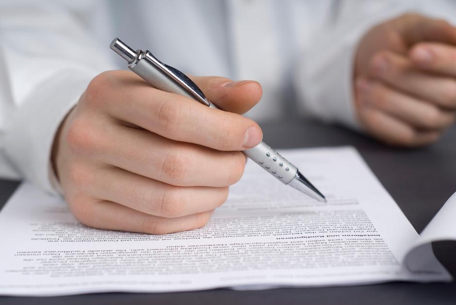 Moški drži v roki pisalo in pregleduje pogodbo | Avtor: Profimedia