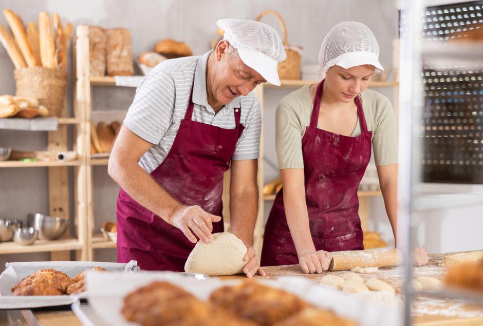 Starejši moški in mlajša ženska mesita kruh | Avtor: Profimedia