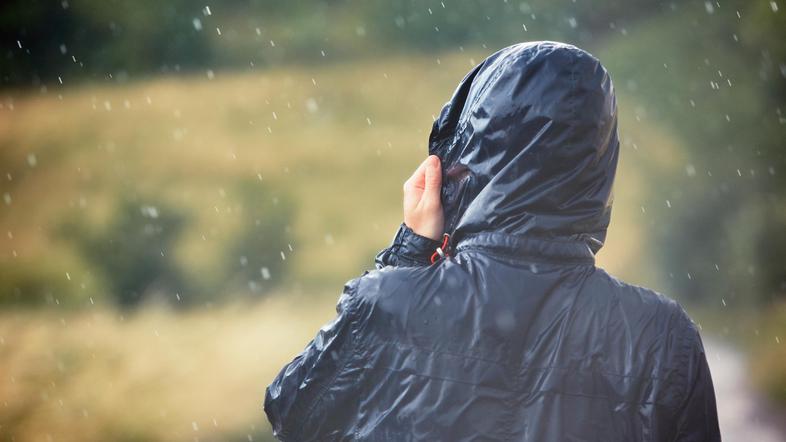 moški v nepremočljivi jakni na sprehodu v dežju