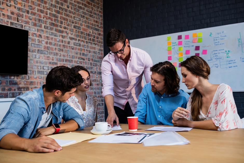 Skupina sodelavcev moški in ženske imajo sestanek, sedijo ob mizi | Avtor: Profimedia