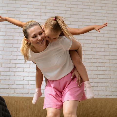 nasmejana mama nosi hčerko na hrbtu