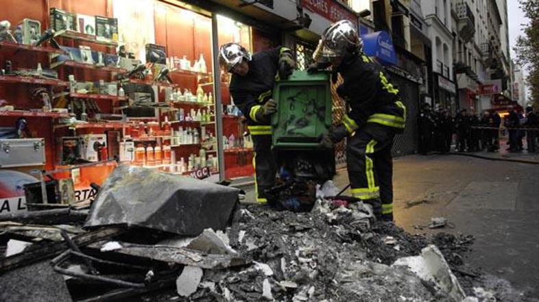 Gasilca preiskujeta okolico stavbe, da bi odkrila vzrok požara.