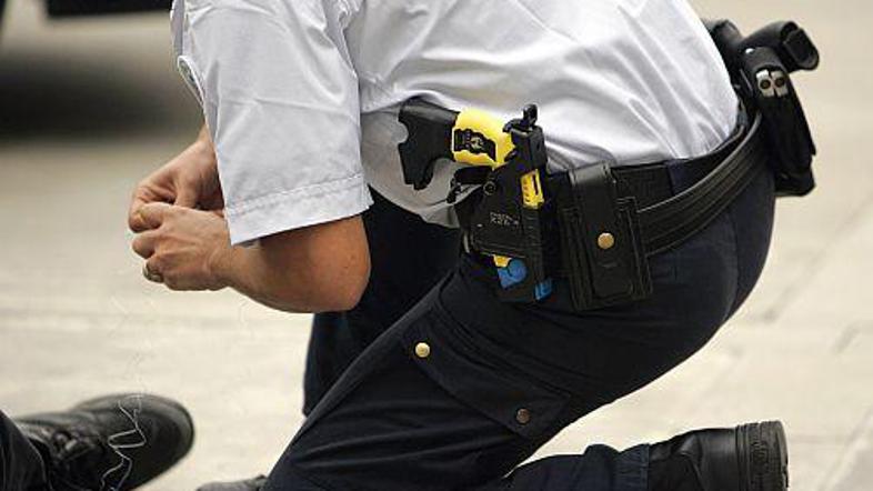 Policist pospravlja žice taserja, ki ga ima spravljenega za pasom.