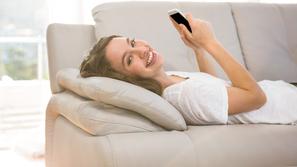 Srečna ženska na kavču s telefonom