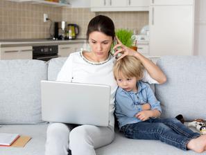 mama telefonira otrok sedi na kavču gledata v prenosni računalnik