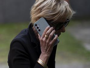 Starejša ženska z očali in telefonom v roki