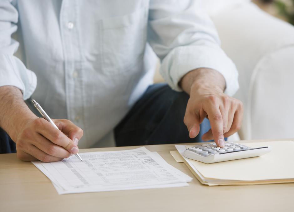 Moški drži v roki svinčnik in kalkulator | Avtor: Profimedia