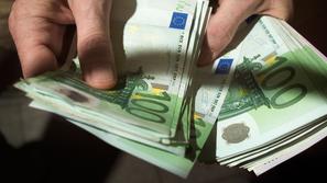 Moški v roki drži denar evre