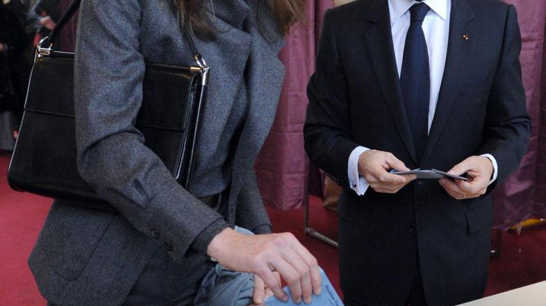 Prva dama Carla Bruni-Sarkozy s soprogom Nicolasom Sarkozyjem na volišču. (Foto: