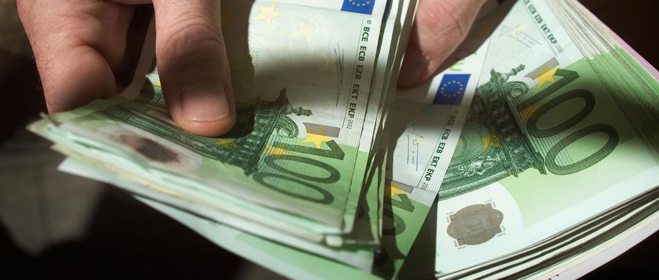 Moški v roki drži denar evre