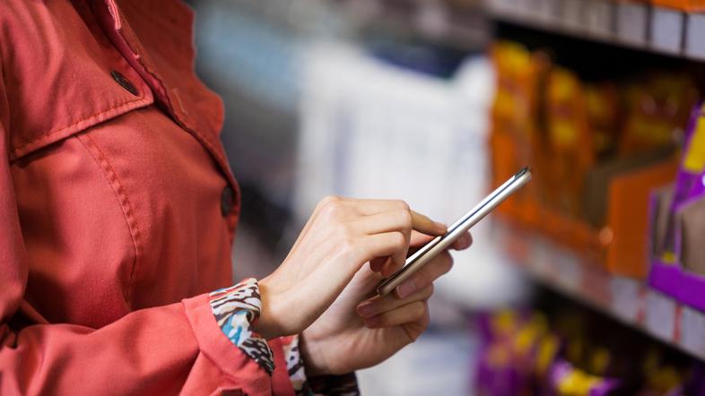 Ženska v roki drži telefon v trgovini